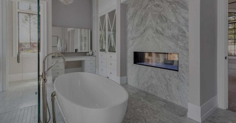 Luxury bathroom with freestanding tub, marble fireplace wall and glass shower